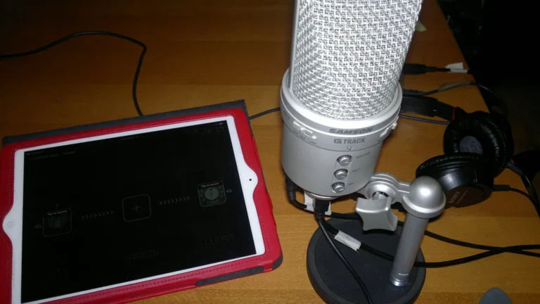 USB condenser microphone and closed-back headphones on a desk, the setup used to record a voice over on PowerPoint