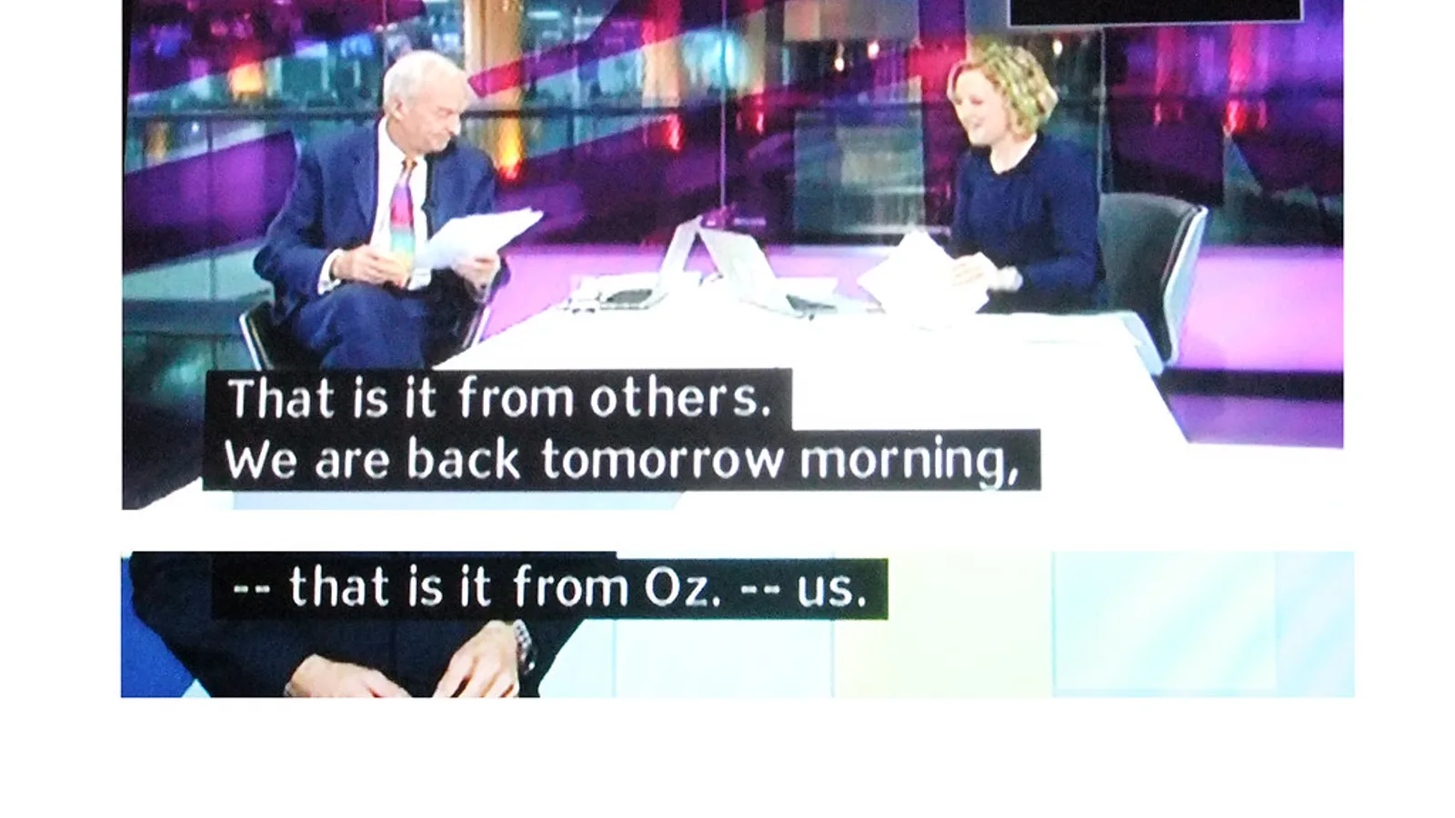 Television screen playing video with a line of subtitle text across the bottom of the frame.